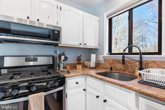 kitchen featuring stainless steel appliances, sink, and white cabinets