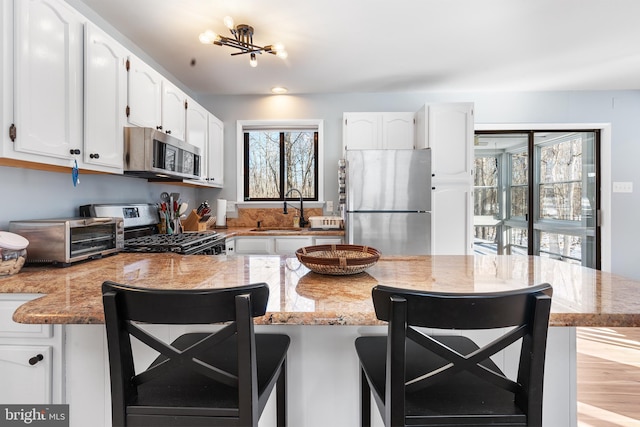 kitchen featuring appliances with stainless steel finishes, sink, a breakfast bar area, and white cabinets