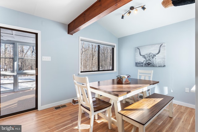 dining area featuring vaulted ceiling with beams and light wood-type flooring