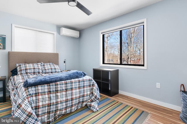 bedroom featuring ceiling fan, a wall mounted AC, and light wood-type flooring