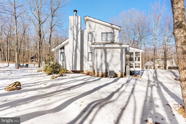 snow covered house with cooling unit and a sunroom