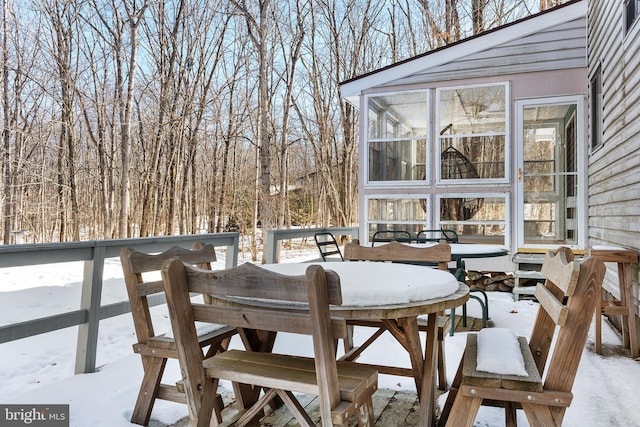 snow covered deck featuring a sunroom