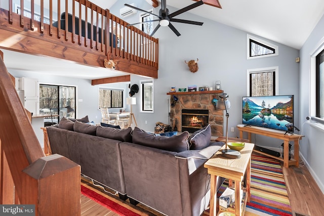 living room featuring a stone fireplace, high vaulted ceiling, ceiling fan, and light hardwood / wood-style flooring