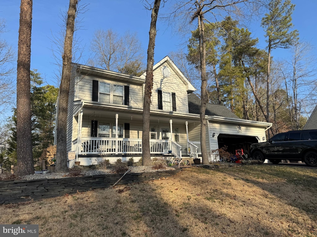 view of front of property featuring a garage, a front lawn, and a porch