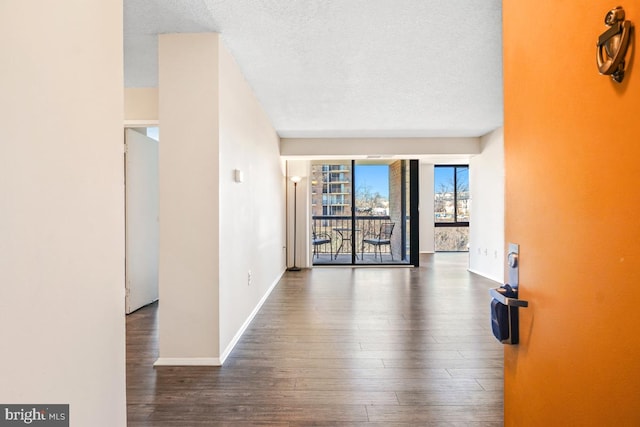 unfurnished room with dark wood-style floors, baseboards, and a textured ceiling