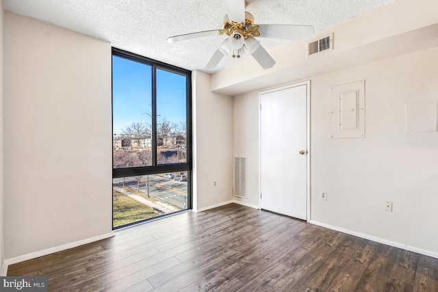 spare room featuring dark wood-style floors, visible vents, floor to ceiling windows, and a textured ceiling