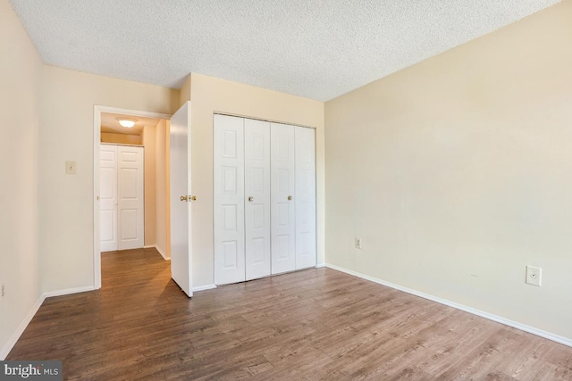 unfurnished bedroom featuring dark wood-style floors, a textured ceiling, and baseboards