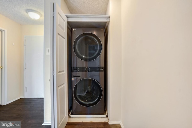 washroom with stacked washer and dryer, laundry area, baseboards, dark wood-style flooring, and a textured ceiling