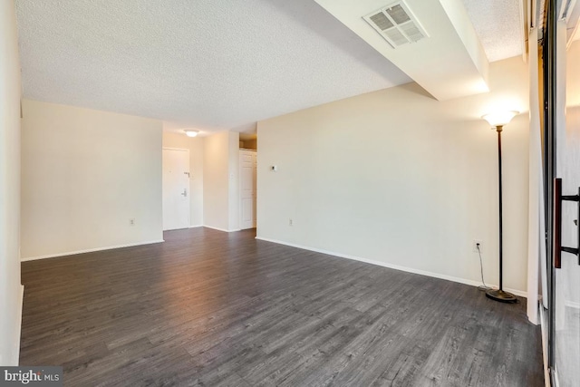 spare room with dark wood-style floors, visible vents, and a textured ceiling