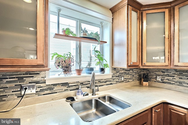 kitchen featuring tasteful backsplash, sink, and light stone counters