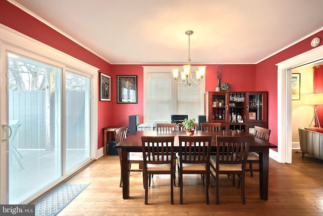 dining space with crown molding, a notable chandelier, and hardwood / wood-style flooring