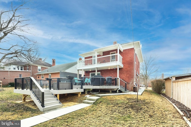 rear view of property featuring a wooden deck, a balcony, and a yard