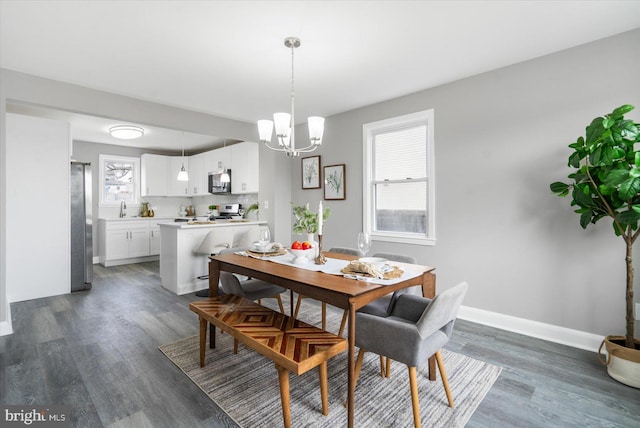 dining room featuring sink, a notable chandelier, and dark hardwood / wood-style flooring