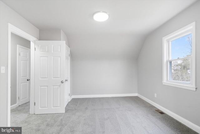 bonus room with lofted ceiling and light colored carpet