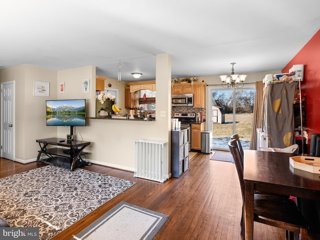 interior space with dark wood-type flooring, appliances with stainless steel finishes, hanging light fixtures, decorative backsplash, and a chandelier