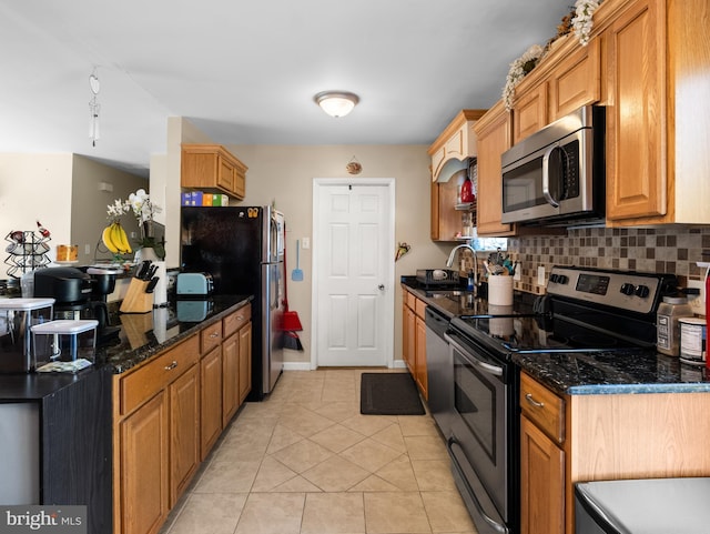 kitchen with appliances with stainless steel finishes, sink, decorative backsplash, and dark stone counters