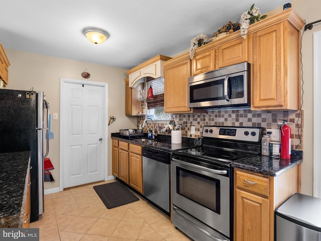 kitchen featuring tasteful backsplash, stainless steel appliances, sink, and dark stone counters