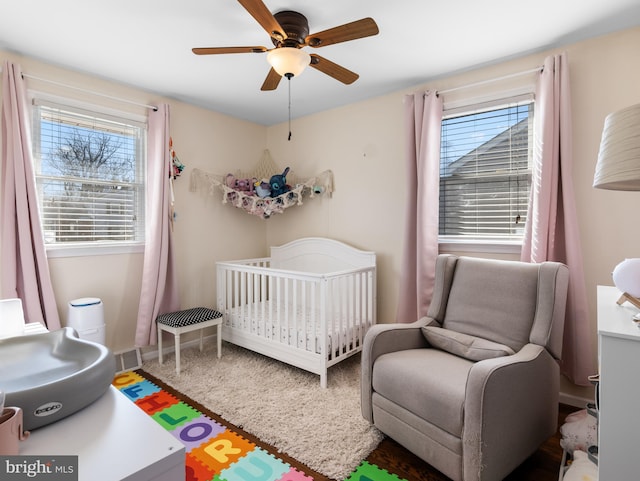 bedroom with a nursery area and ceiling fan