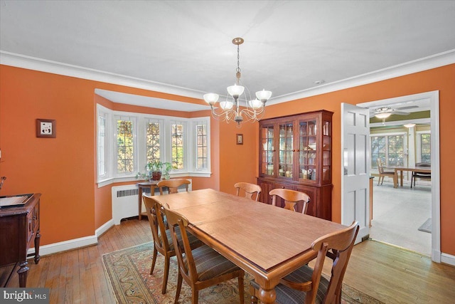 dining area with light hardwood / wood-style flooring, radiator heating unit, ornamental molding, and an inviting chandelier