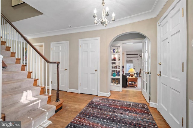 entrance foyer featuring crown molding, a chandelier, and light hardwood / wood-style flooring