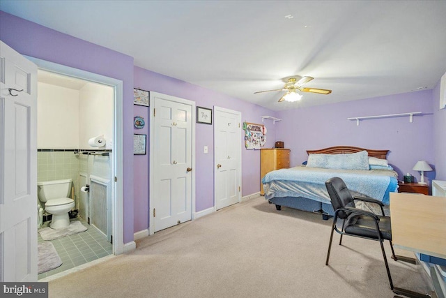 bedroom featuring connected bathroom, light carpet, and ceiling fan