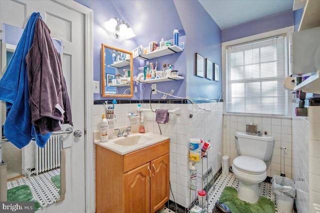 bathroom featuring vanity, radiator heating unit, tile walls, and toilet