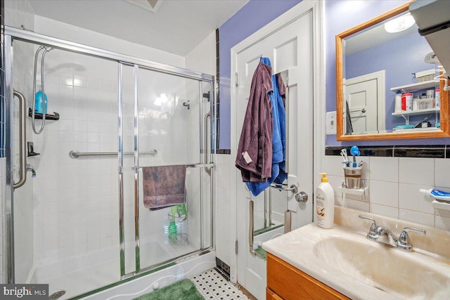 bathroom with tile walls, vanity, and a shower with shower door