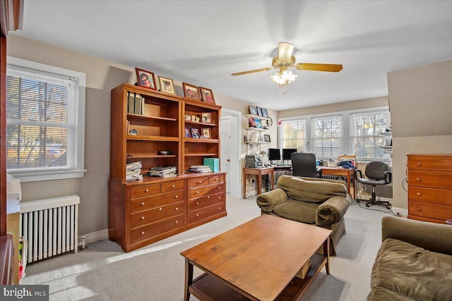 office space with ceiling fan, radiator heating unit, and light carpet