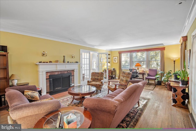 living room with ornamental molding, a wealth of natural light, a fireplace, and light hardwood / wood-style flooring