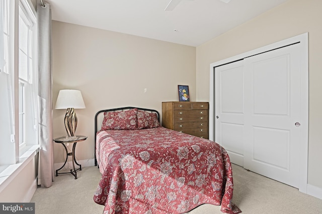 bedroom with light carpet, ceiling fan, and a closet