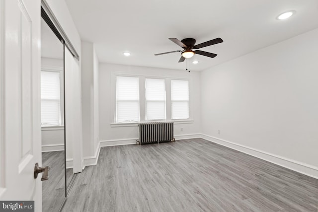 unfurnished bedroom with baseboards, radiator heating unit, recessed lighting, and light wood-style floors