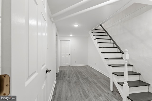 below grade area with recessed lighting, stairway, baseboards, and wood finished floors