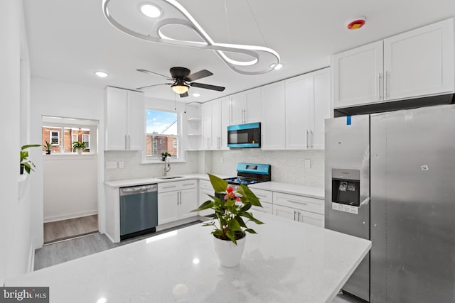 kitchen with tasteful backsplash, white cabinets, hanging light fixtures, stainless steel appliances, and open shelves