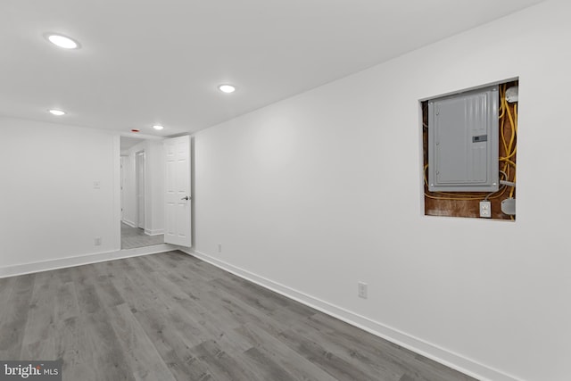 spare room with light wood-style floors, recessed lighting, electric panel, and baseboards