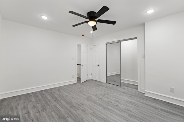 unfurnished bedroom featuring light wood-style flooring, baseboards, a closet, and recessed lighting