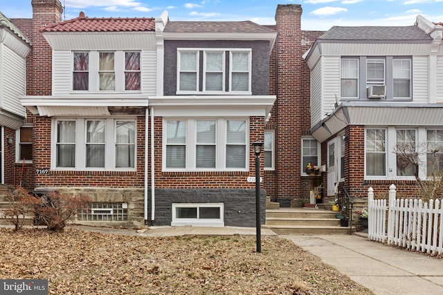 view of property featuring a chimney, fence, cooling unit, and brick siding