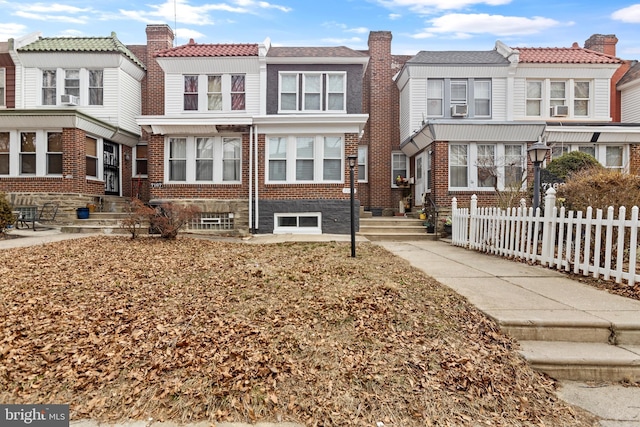 view of front of property with a chimney, fence, cooling unit, and brick siding