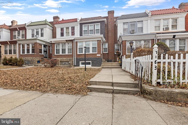 view of property with a fenced front yard, a residential view, and brick siding