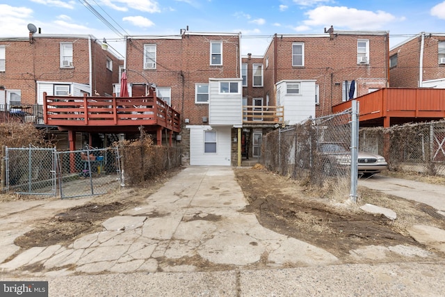 back of property with a deck, brick siding, and fence