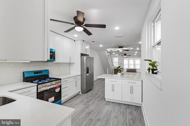 kitchen featuring stainless steel appliances, light countertops, light wood-style flooring, white cabinets, and a peninsula