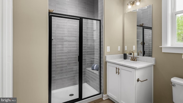 bathroom with walk in shower, vanity, and toilet