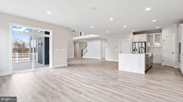 kitchen featuring an island with sink, light hardwood / wood-style flooring, white cabinets, and stainless steel fridge with ice dispenser