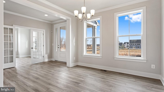 foyer with crown molding, light hardwood / wood-style floors, french doors, and a chandelier