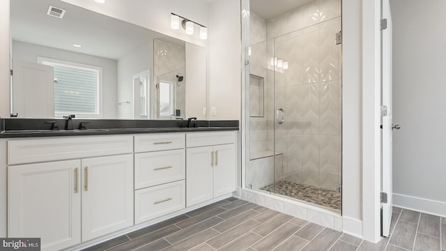 bathroom with a shower with door and vanity