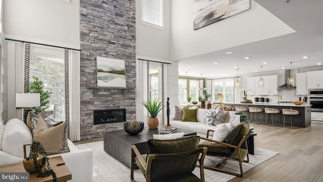 living room with a fireplace, light hardwood / wood-style flooring, and a high ceiling