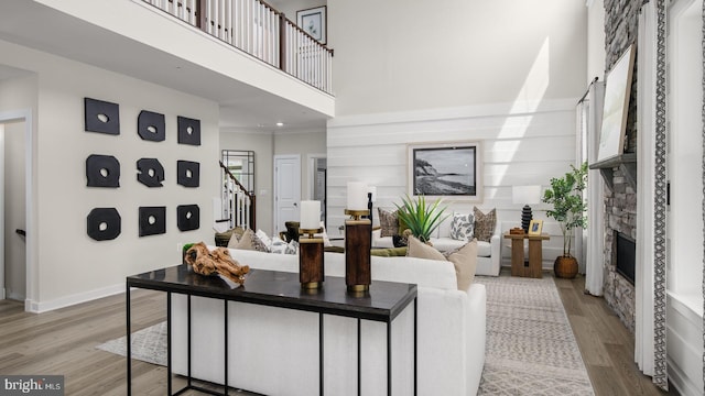 living room featuring wood-type flooring, a towering ceiling, and a fireplace