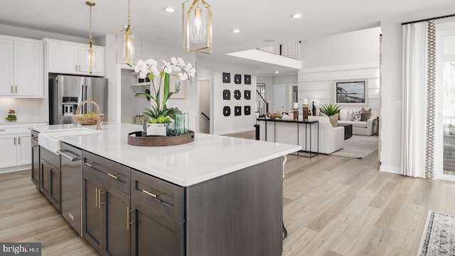 kitchen featuring white cabinetry, stainless steel refrigerator with ice dispenser, hanging light fixtures, and light hardwood / wood-style flooring