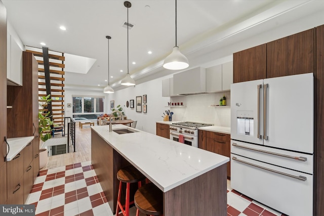 kitchen featuring hanging light fixtures, sink, a kitchen island with sink, and premium appliances