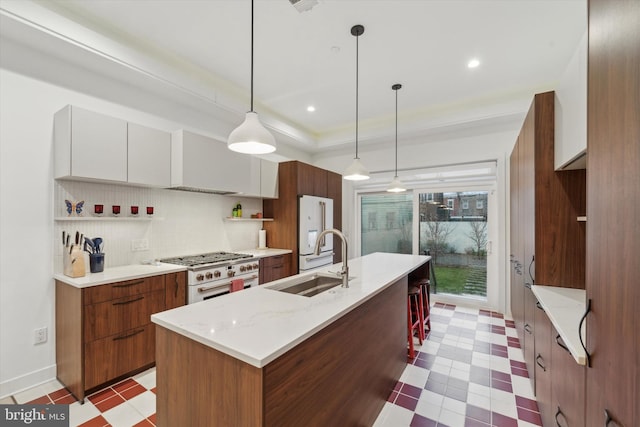 kitchen featuring sink, white cabinetry, hanging light fixtures, a kitchen island with sink, and premium appliances