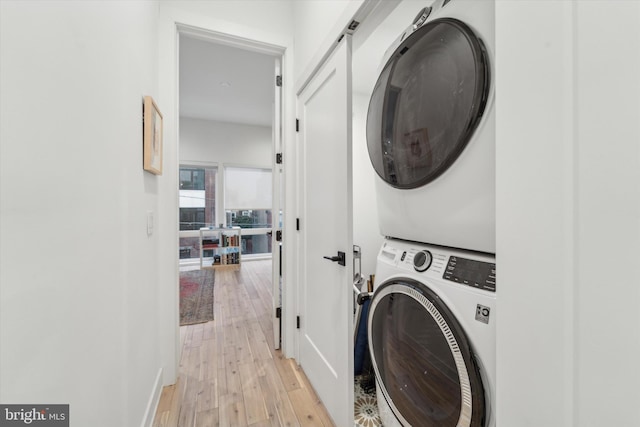 clothes washing area with light hardwood / wood-style flooring and stacked washer and clothes dryer